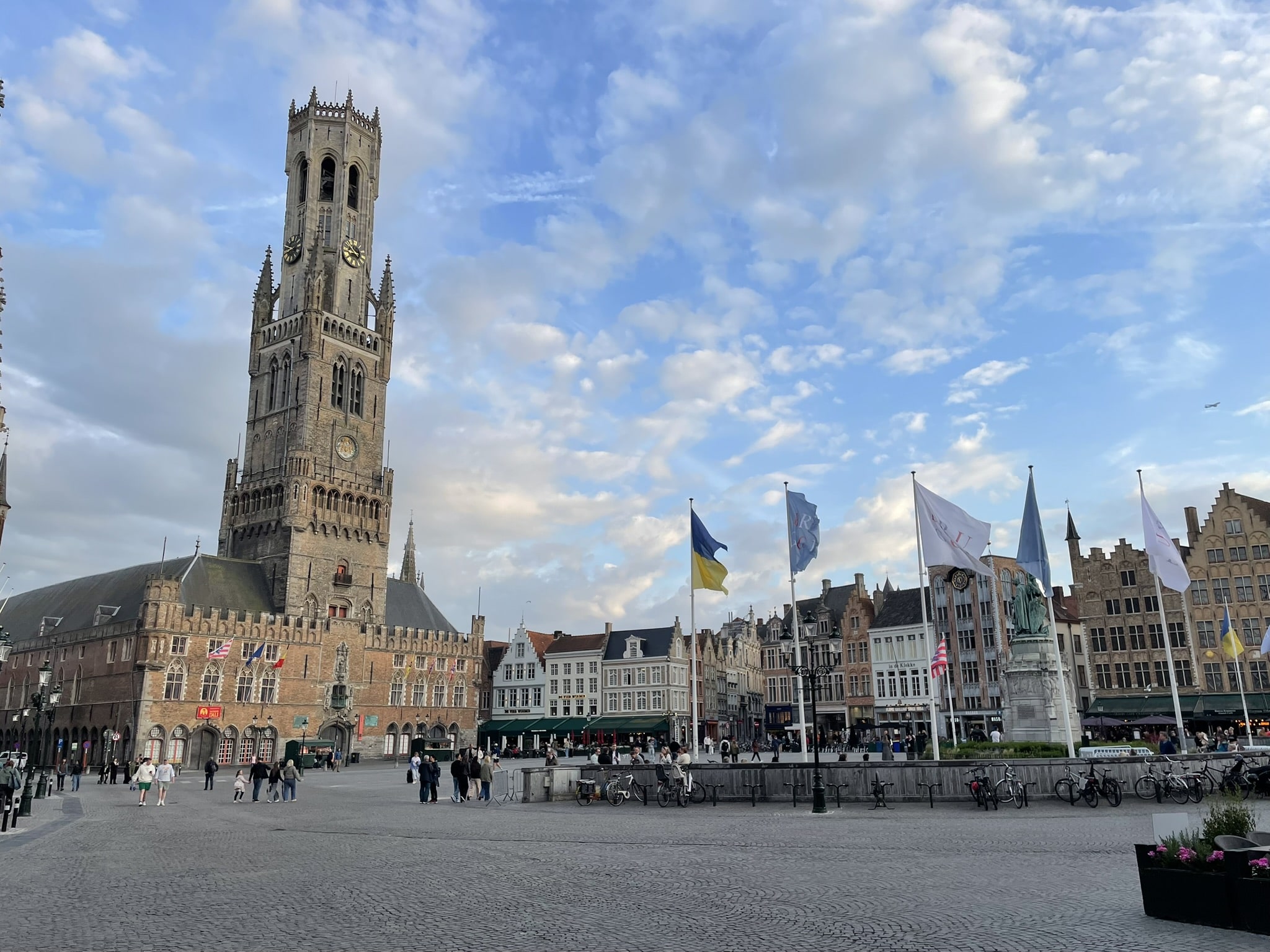 medeieval town square featuring a brick building with a very tall clock tower