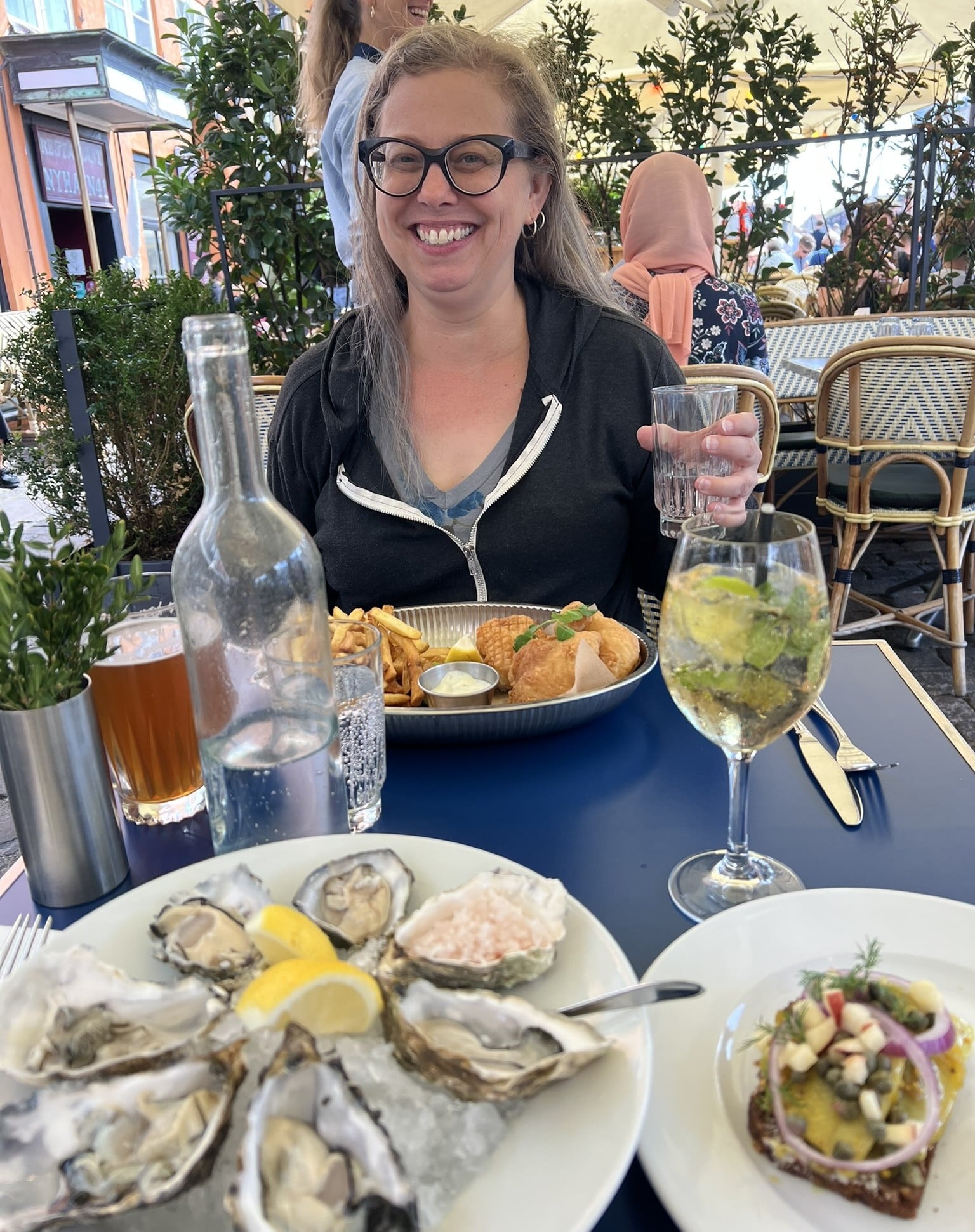 Woman sitting at an outdoor table in front of a plate of oysters
