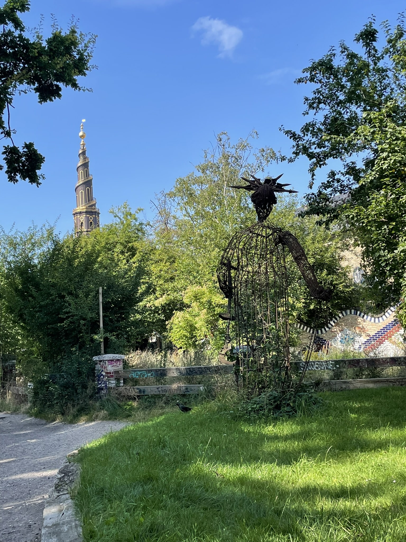 cage-like statue with spiral church tower in the disance