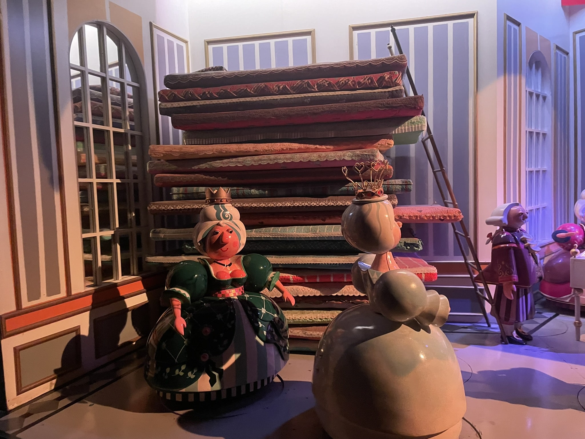 cartoon like display of plump women in front of many mattresses piled up