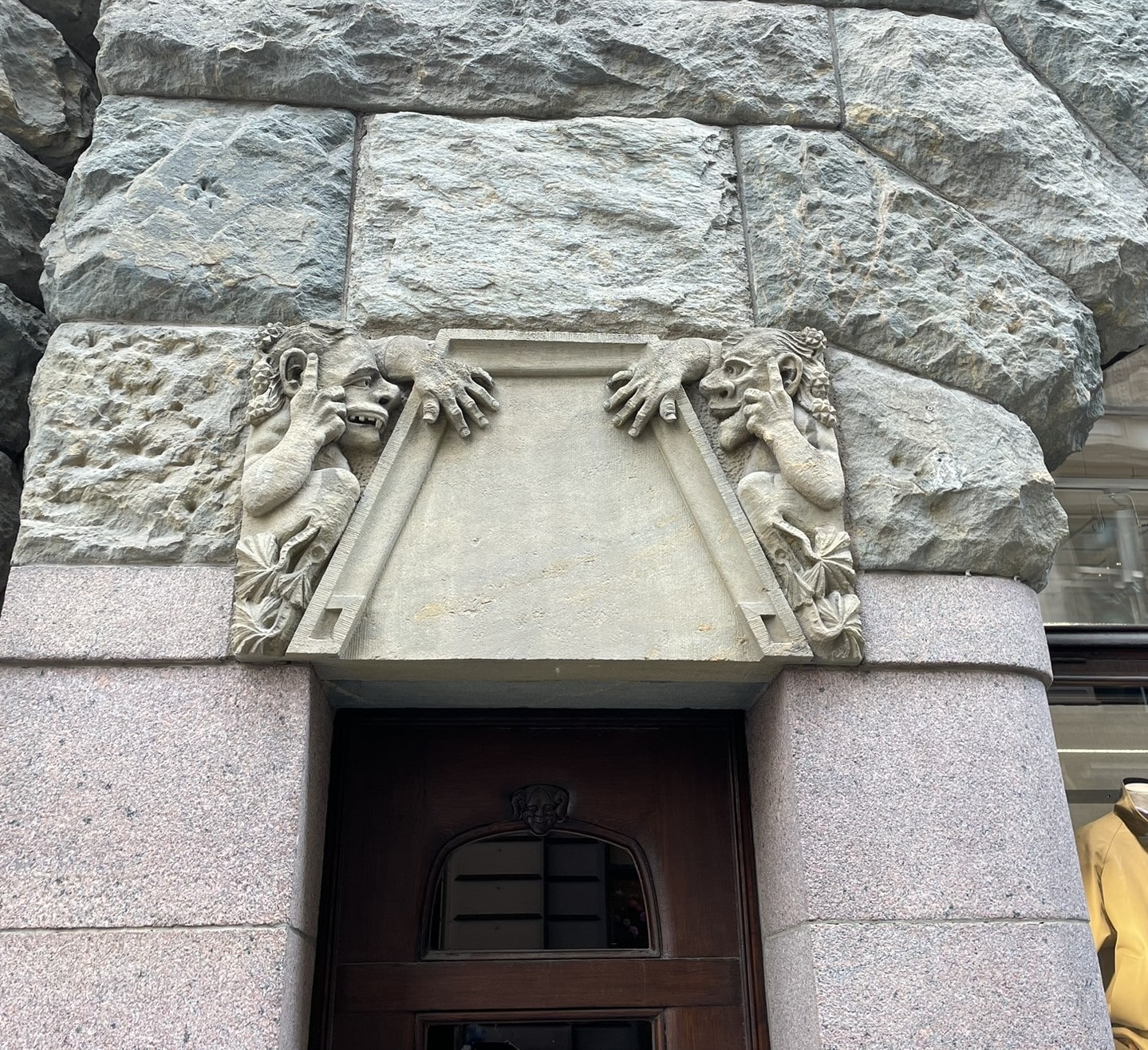 Doorway of a stone building with troll like creatures carved above the doorway