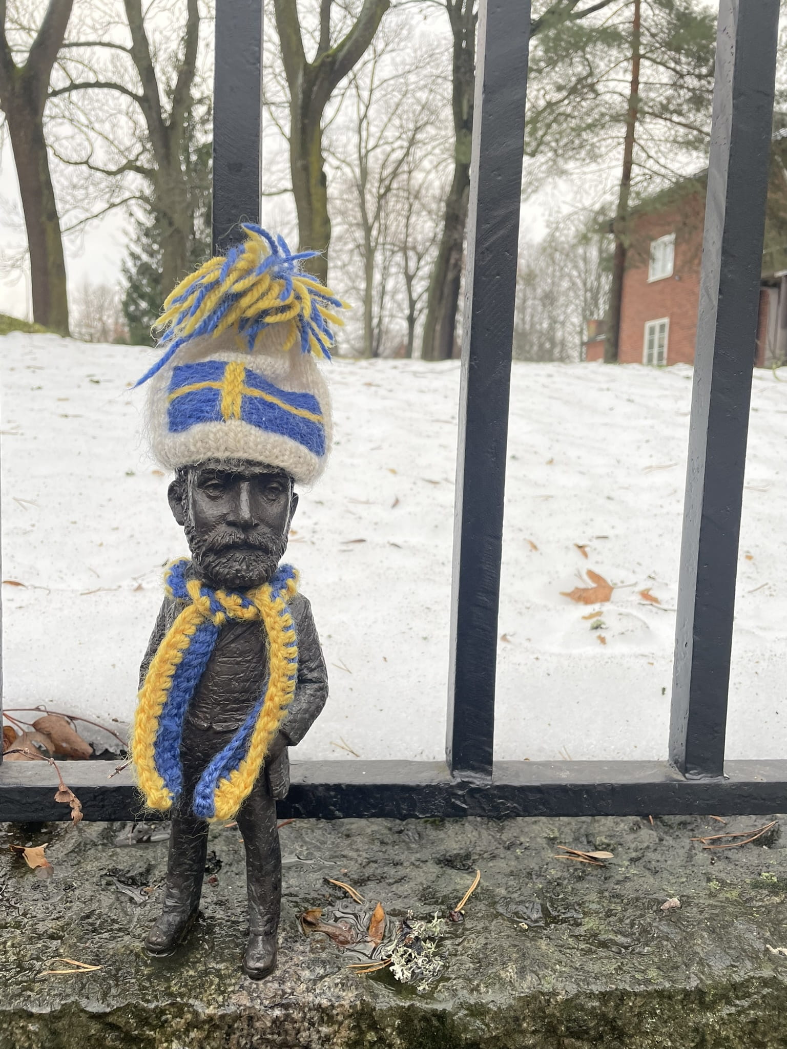 tiny statue wearing a blue and yellow knit hat and scarf