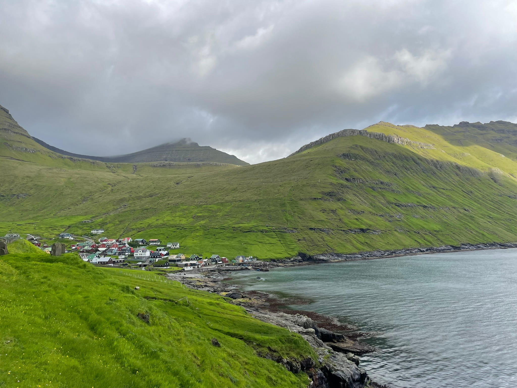 Green hills over a waterfront, with some houses in the distance