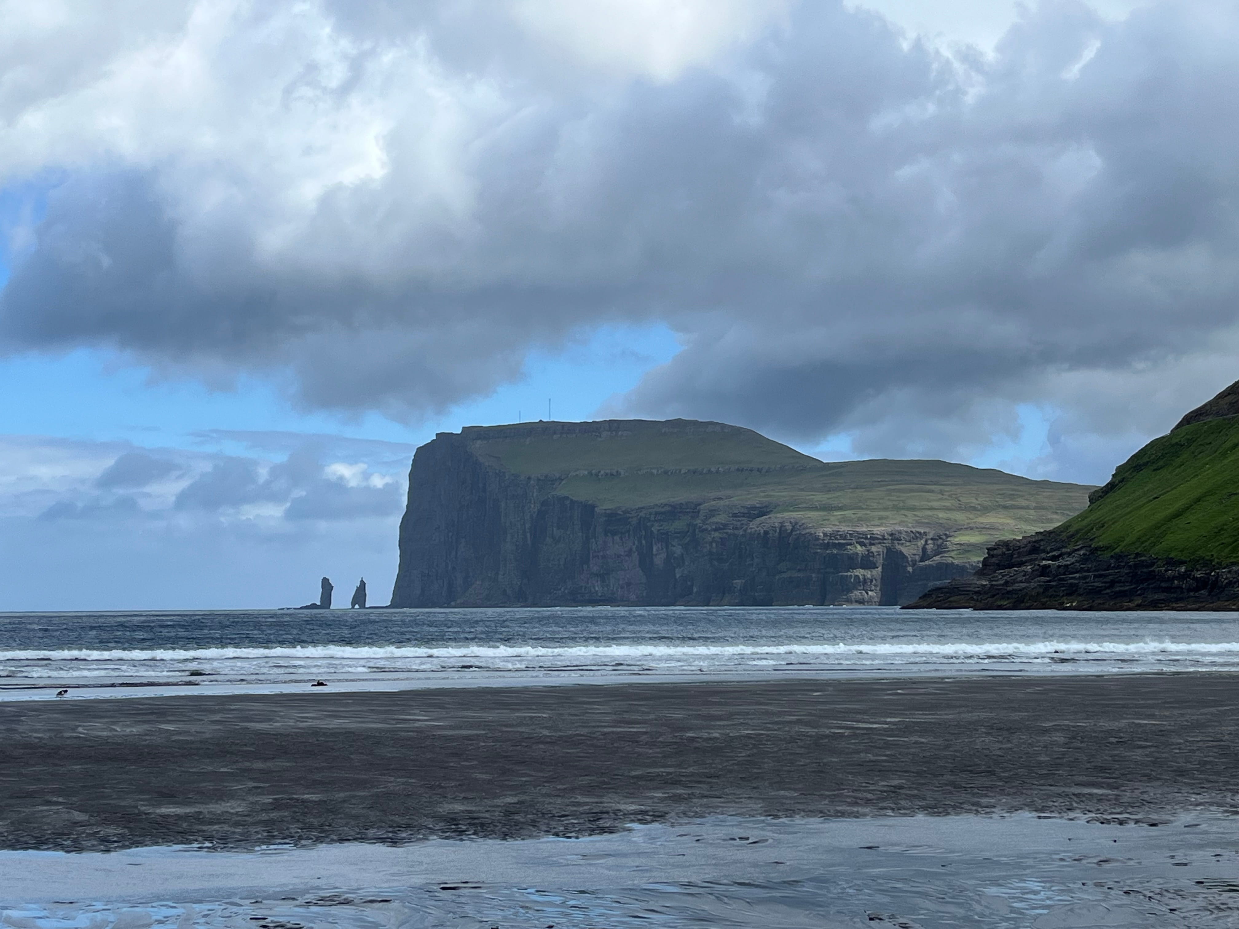 View from a beachfront of seas stacks under a looming cliff