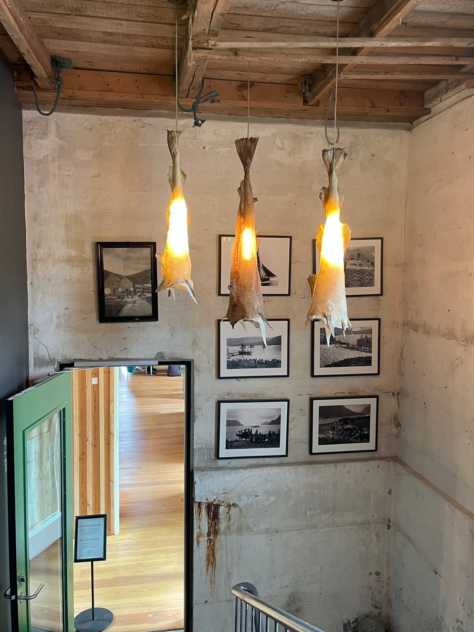 three hanging lamps made of dried cod with a cerement wall behind