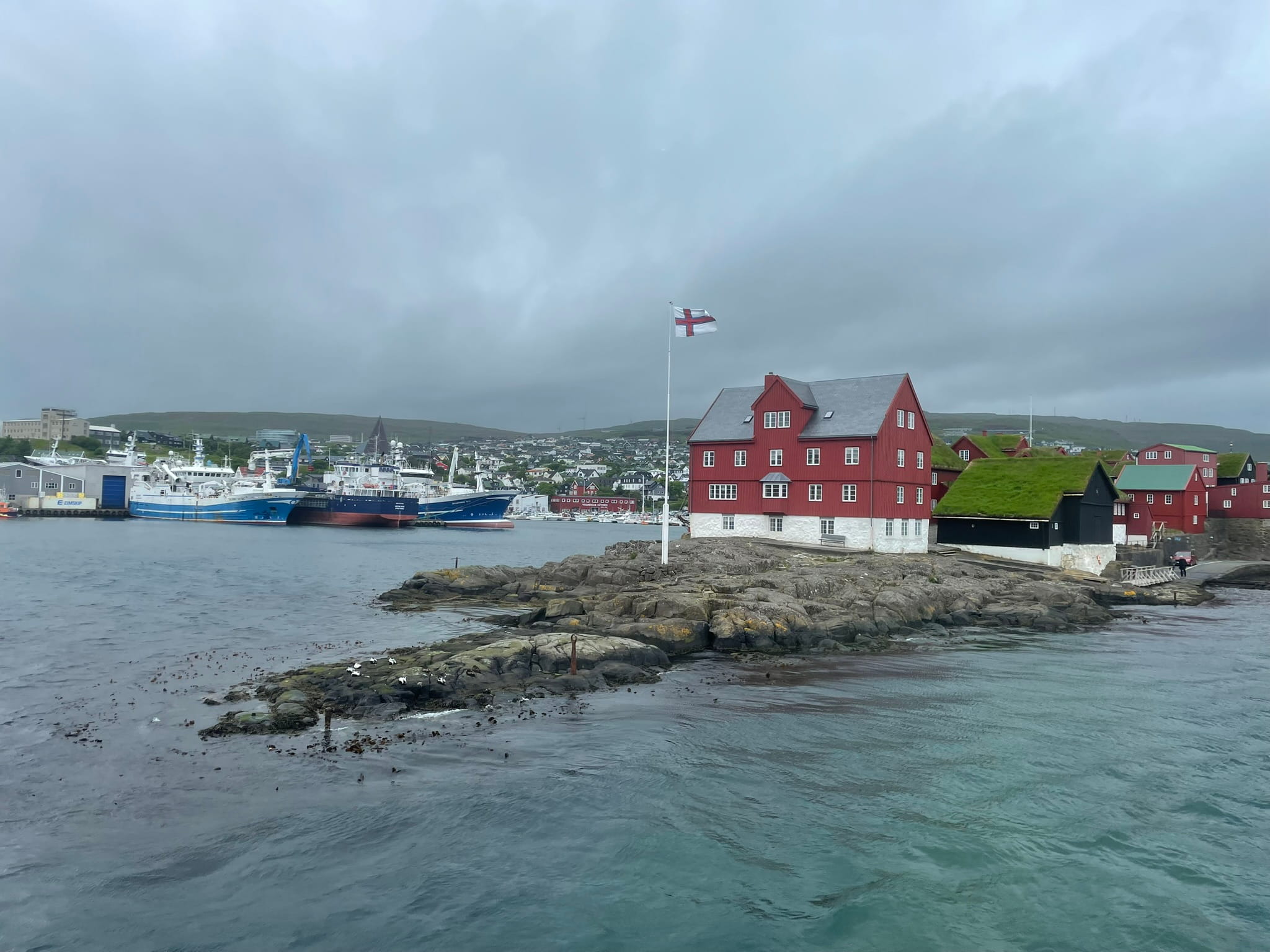 rocky area in the sea, featuring a red building fronted by a Faroese flag