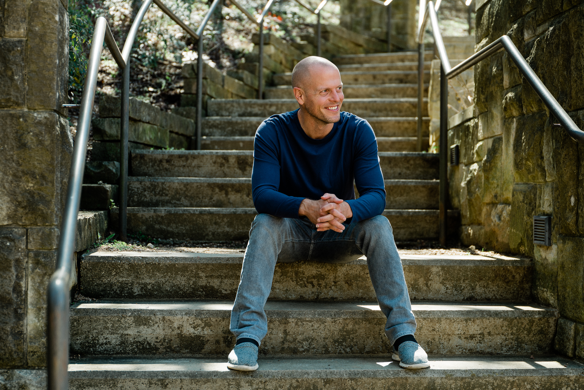 Tim Ferriss sitting outdoors on some stone steps and smiling.