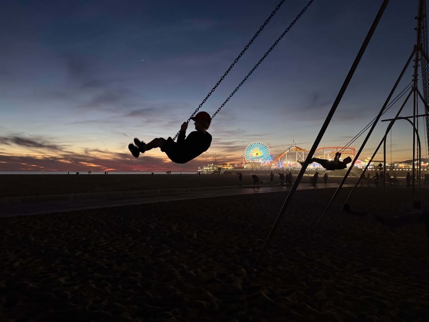 Child on swing at sunset with Santa Monica Beach in background