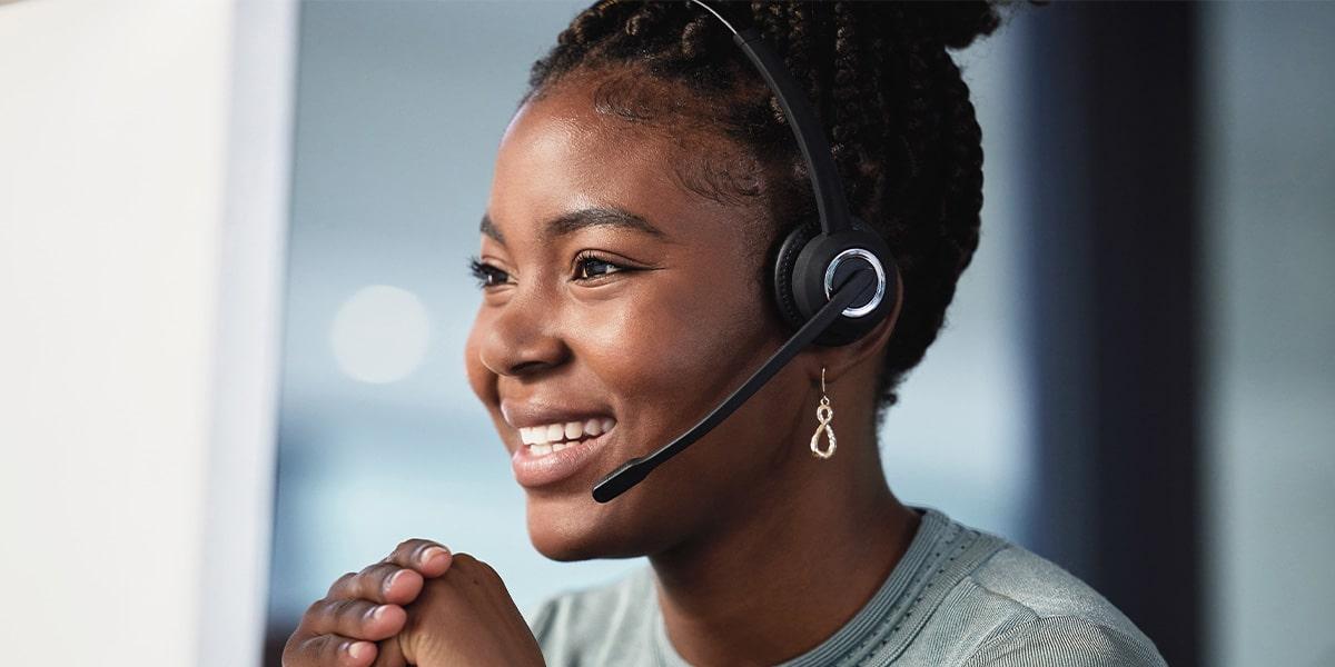 Smiling woman with headset in office setting.