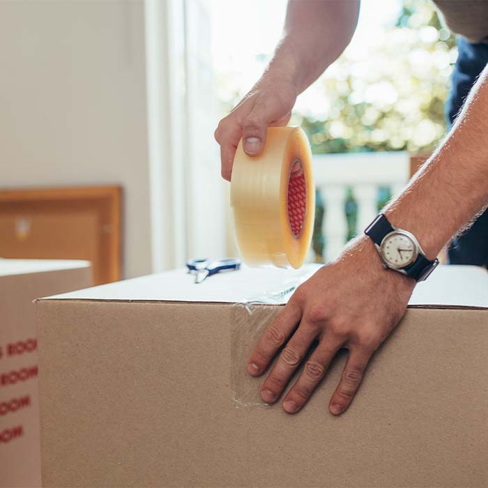 Person taping a cardboard moving box.
