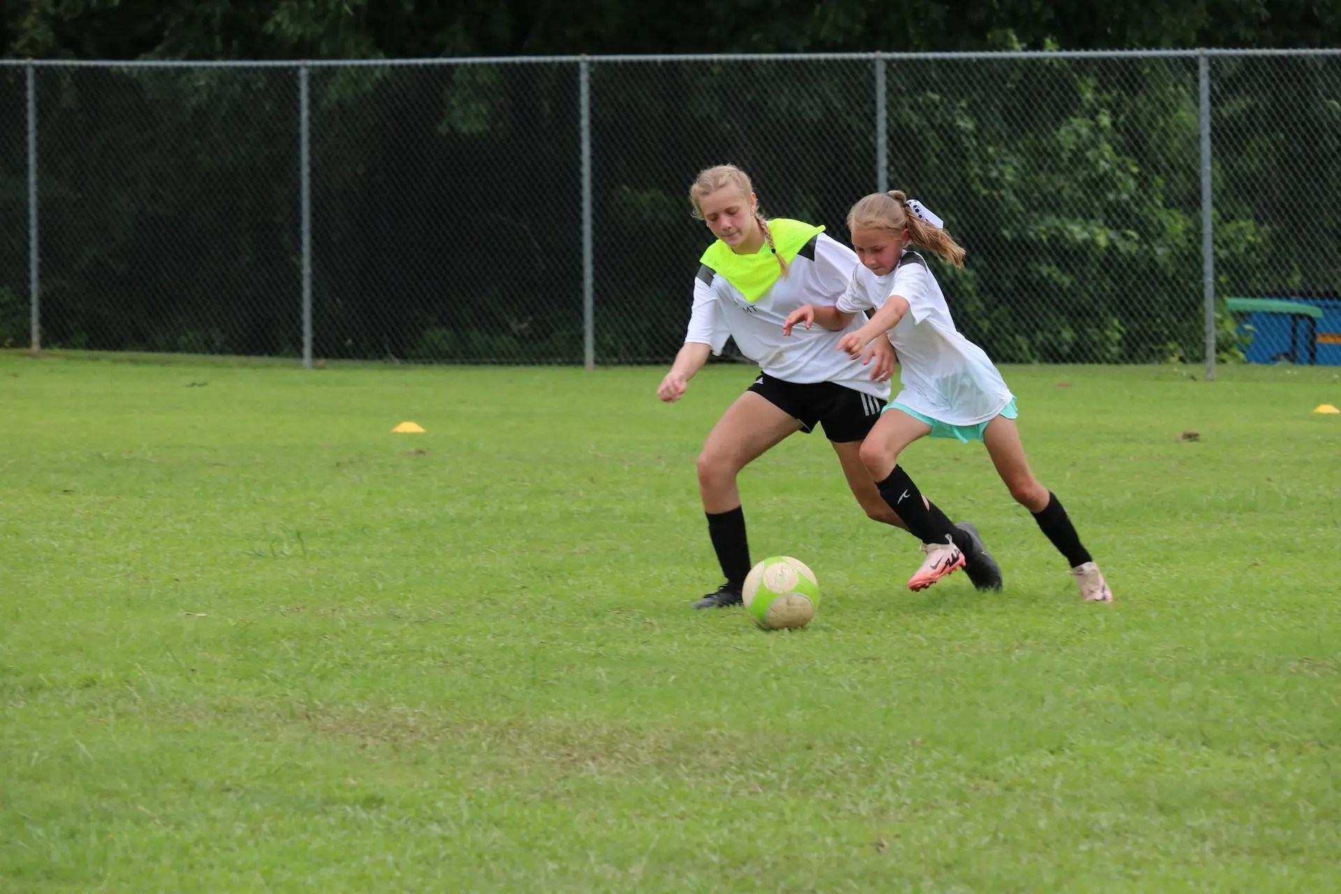 Two girls competing in a 1v1 situation in a soccer camp.