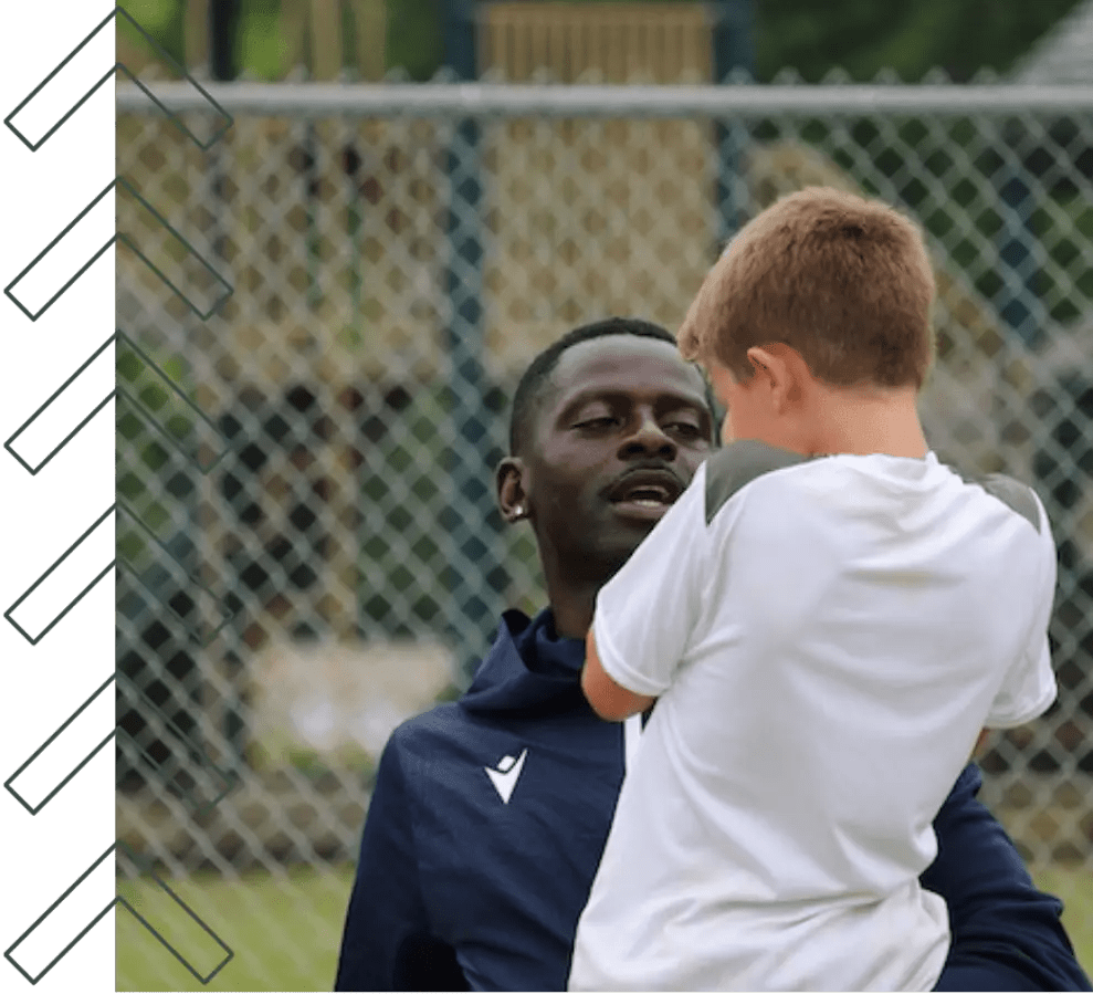 Coach Dennis holds a player in his arms.