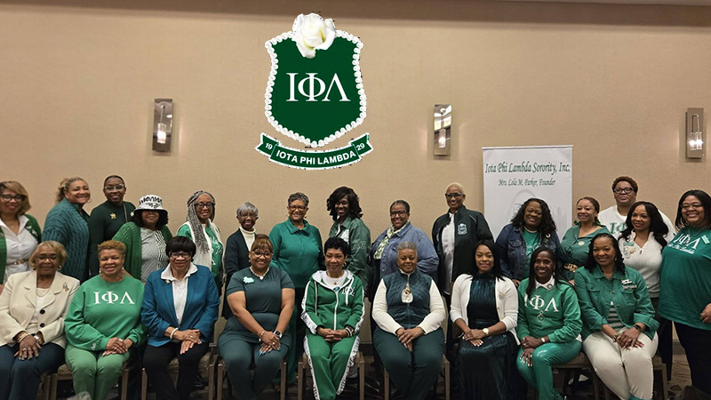 Group photo of Iota Phi Lambda members in green and white attire, showcasing the first African American business sorority's emblem and banner.