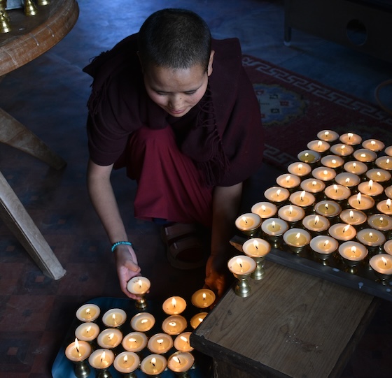 Tibetan Buddhist nun lights butter lamps