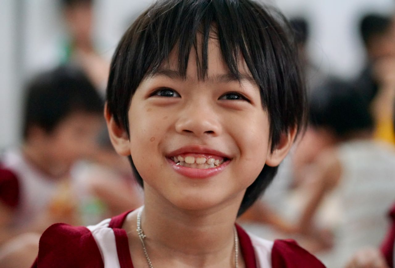 A smiling child looks toward the camera at the Center for Innocent Children in Vietnam.