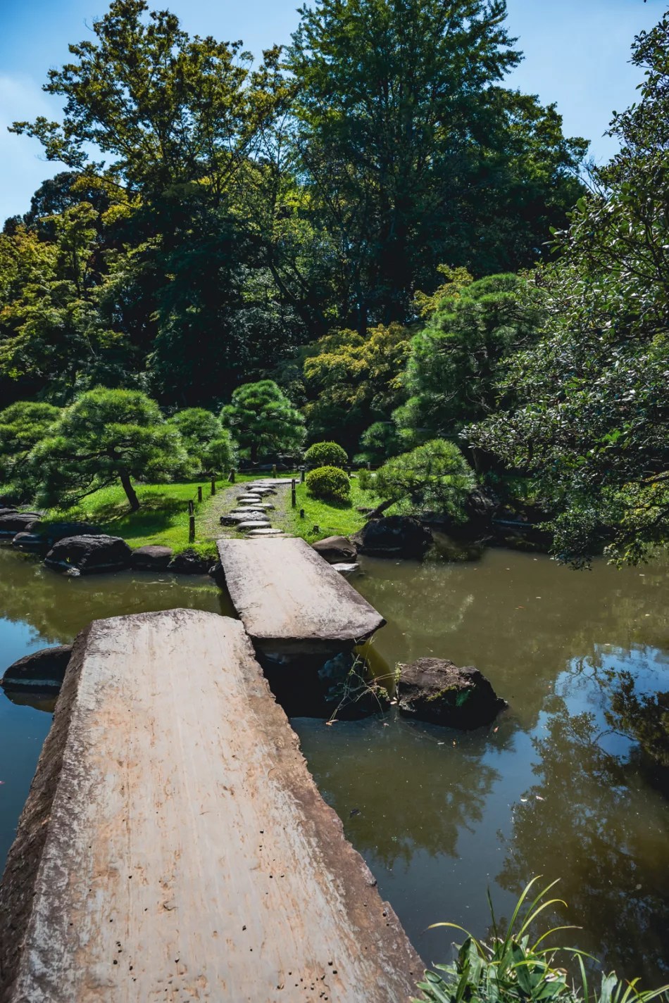 stone bridge across a pond in a japanese garden