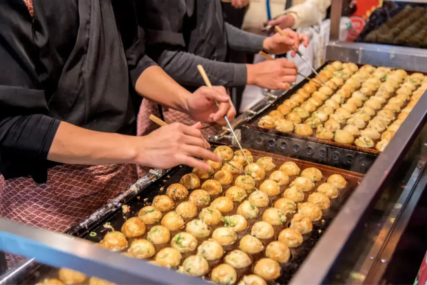 People making takoyaki (octopus balls) at a summer festival.