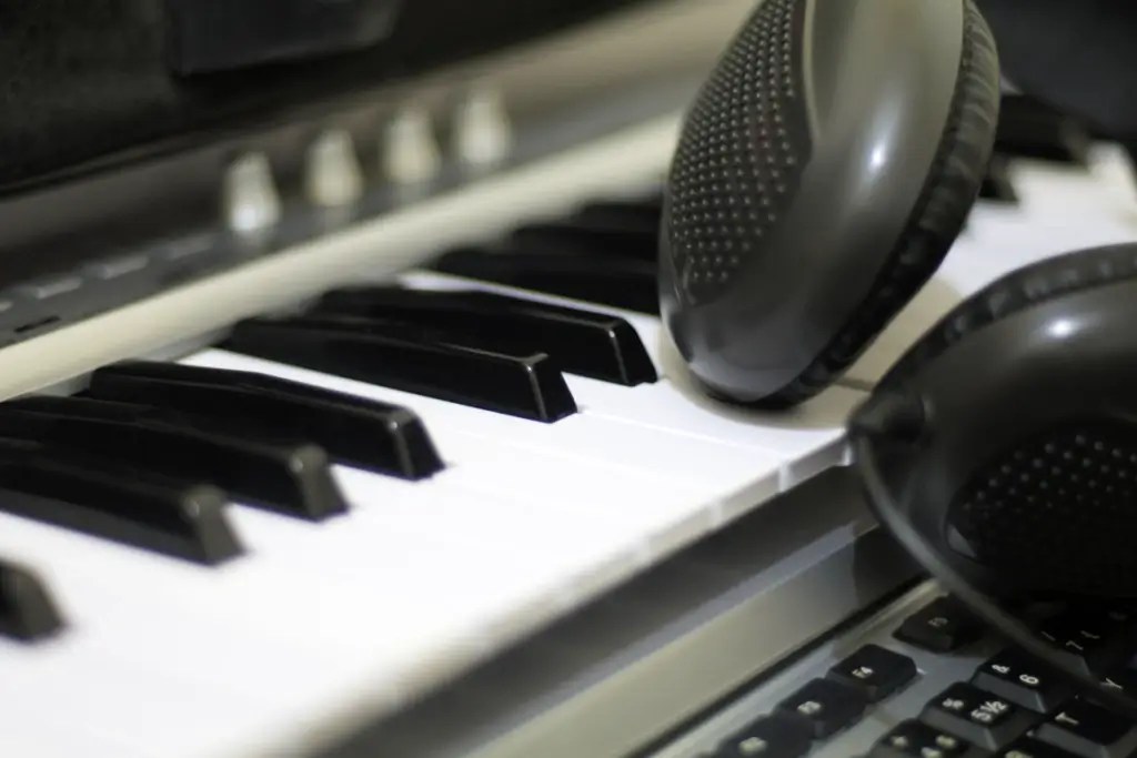 A pair of headphones resting on the white keys of a Casio keyboard.
