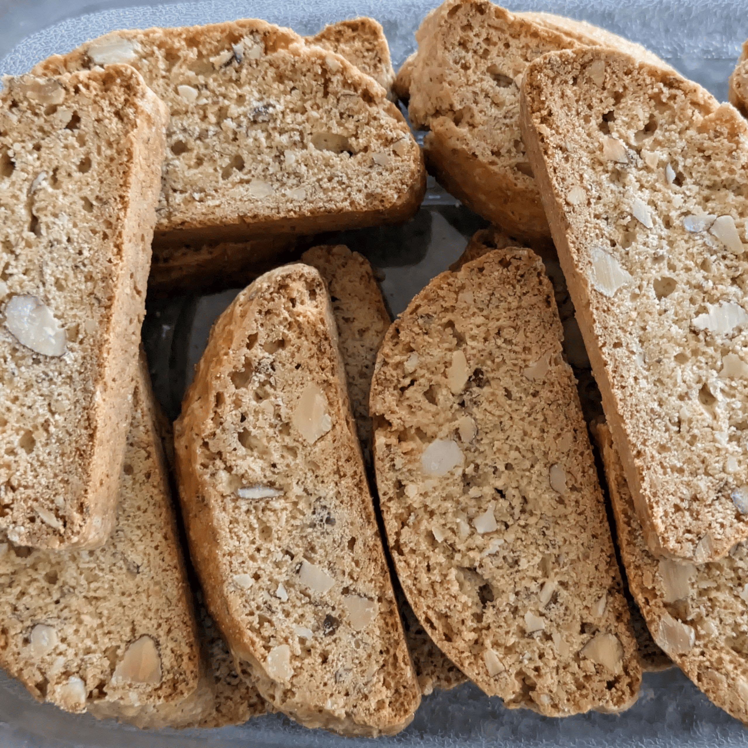 Numerous almond biscotti are stacked and scattered, revealing their crunchy texture and embedded nuts.