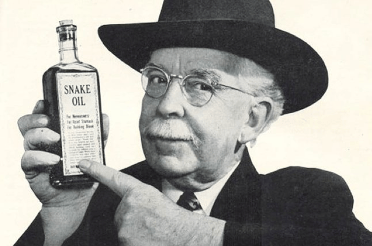 Vintage photo of a man in a hat and glasses pointing to a bottle labeled "Snake Oil"