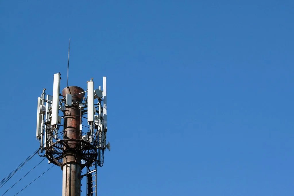 A cell tower with antennas against a clear blue sky