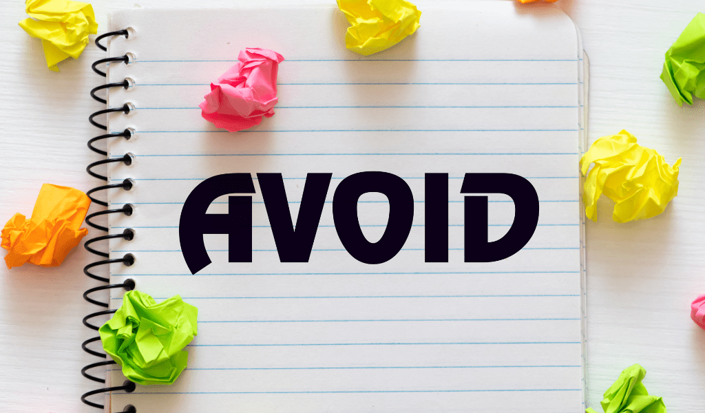 The word avoid written on lined paper in a spiral notebook surrounded by coloured balls of scrunched up paper.