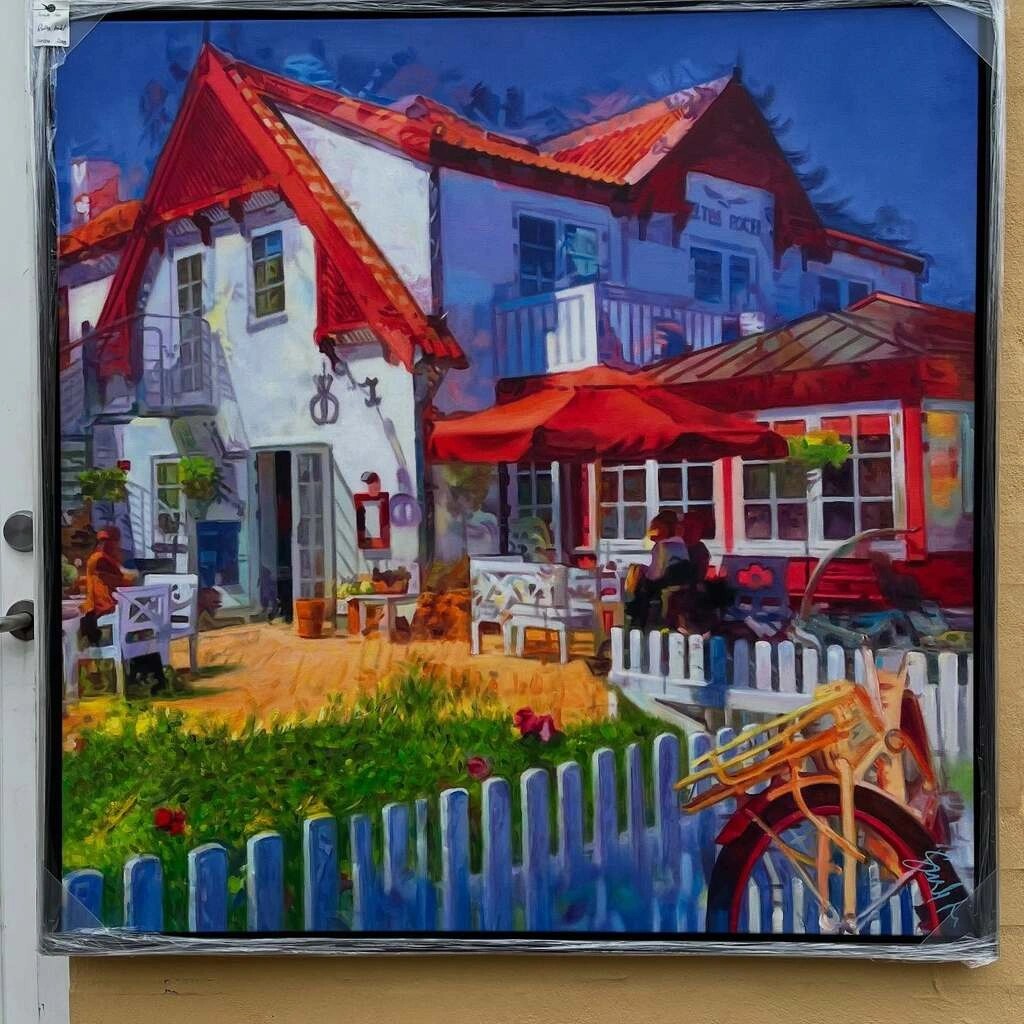 Farverigt maleri af Ruths Hotel i Skagen med rød tagkonstruktion, hvide vægge, parasoller og en cykel i forgrunden, udstillet hos Galleri Bo