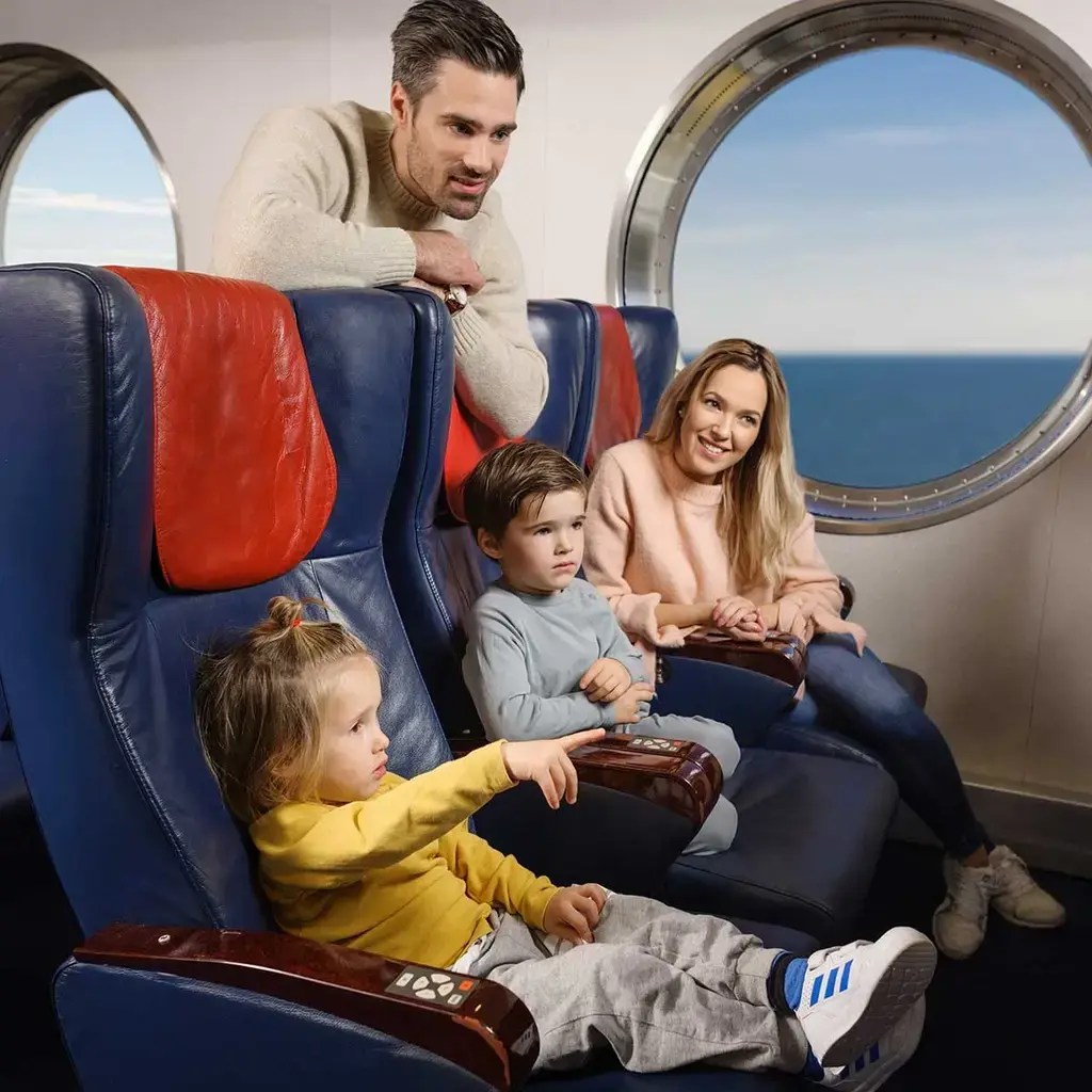 Familie med to børn nyder sejlturen på en Color Line-færge og ser ud over havet gennem et stort rundt vindue.