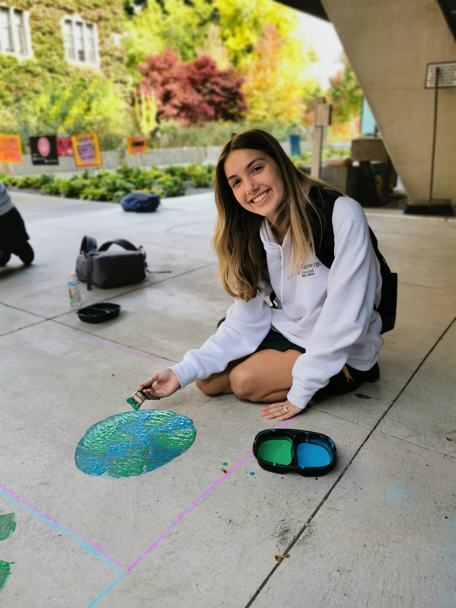 Student displaying art on sidewalk.