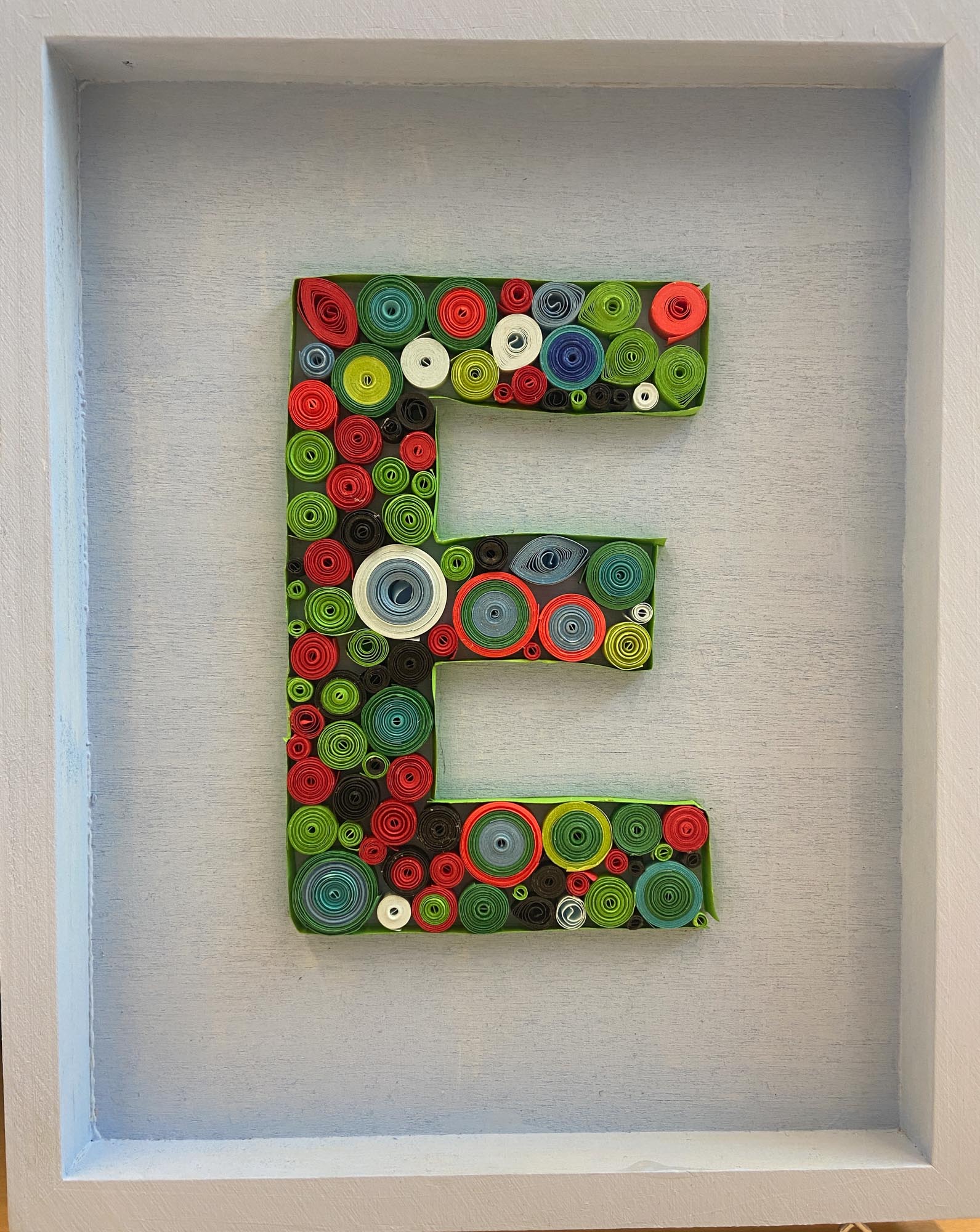 The letter E made from quill art.