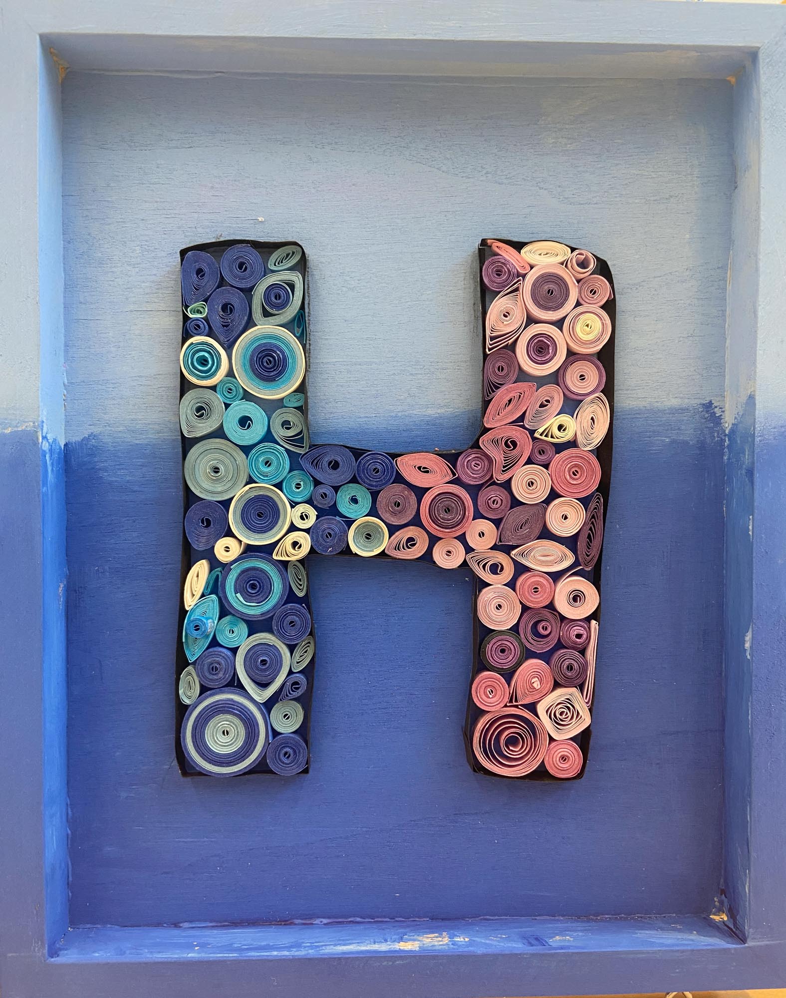 The letter H made from quill art.