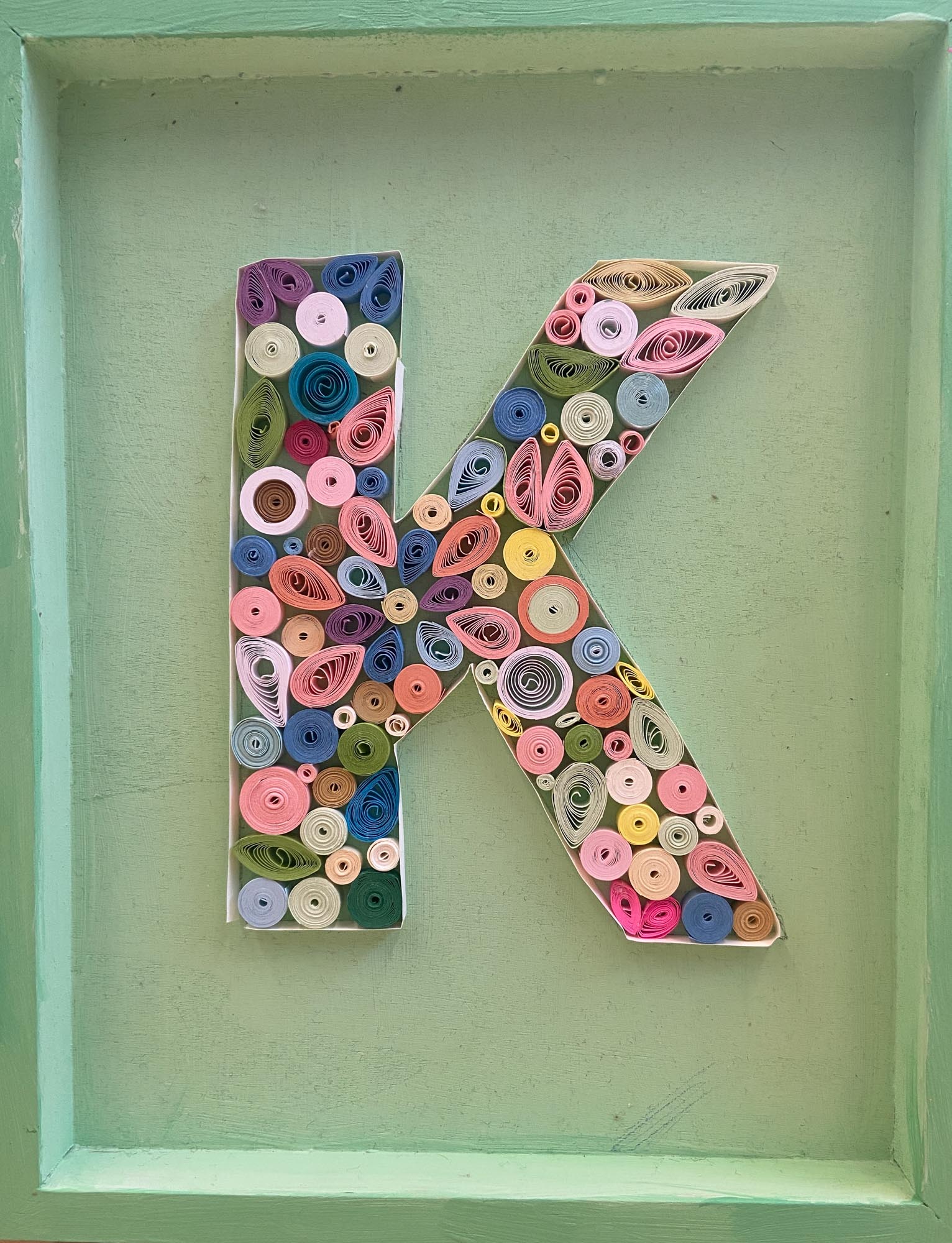 The letter K made from quill art.