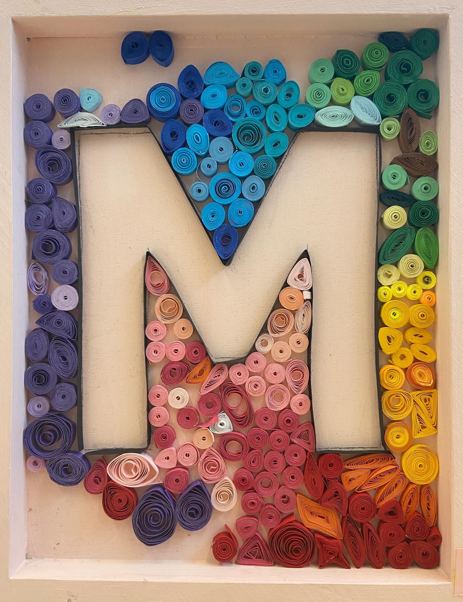 The letter M made from quill art.