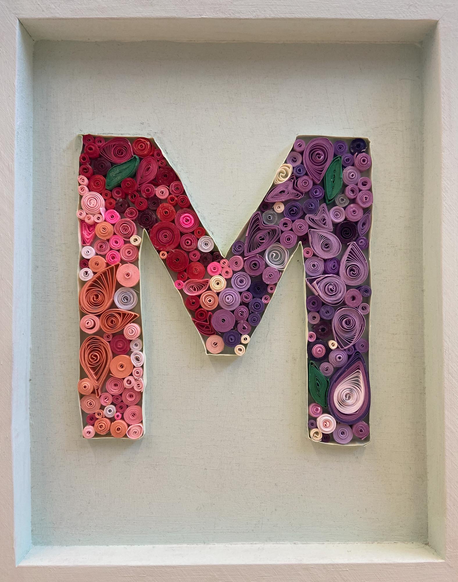 The letter M made from quill art.