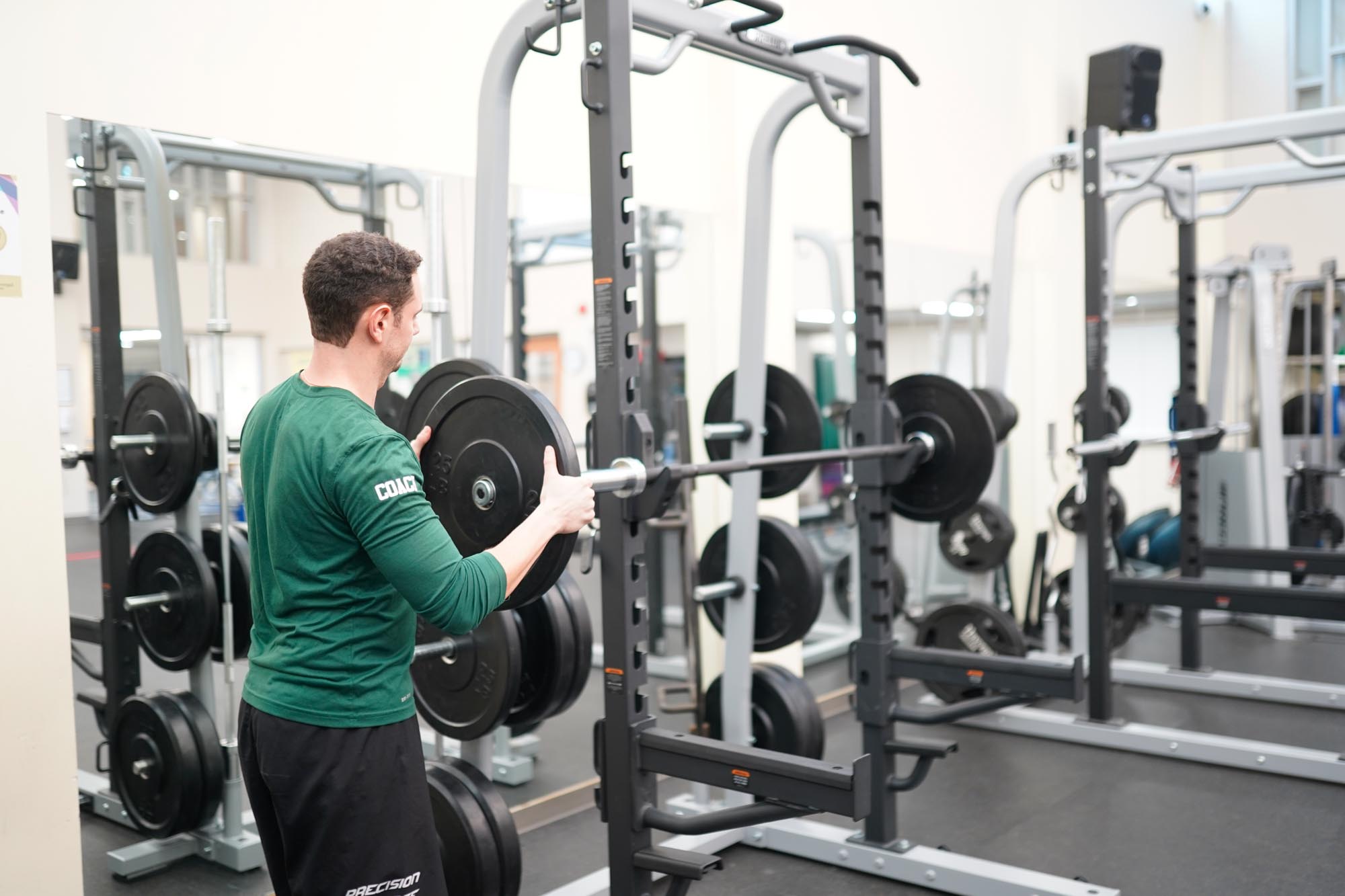 Havergal Strength and Conditioning Coach demonstrating how to put on a weight onto a barbell.