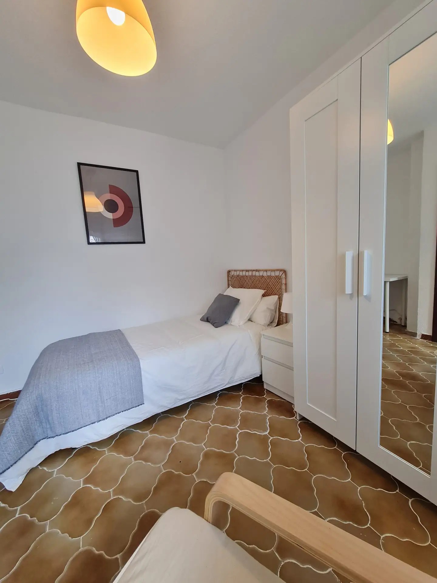 Amplia habitación con cama, cabecero, mesilla de noche, cuadro y armario