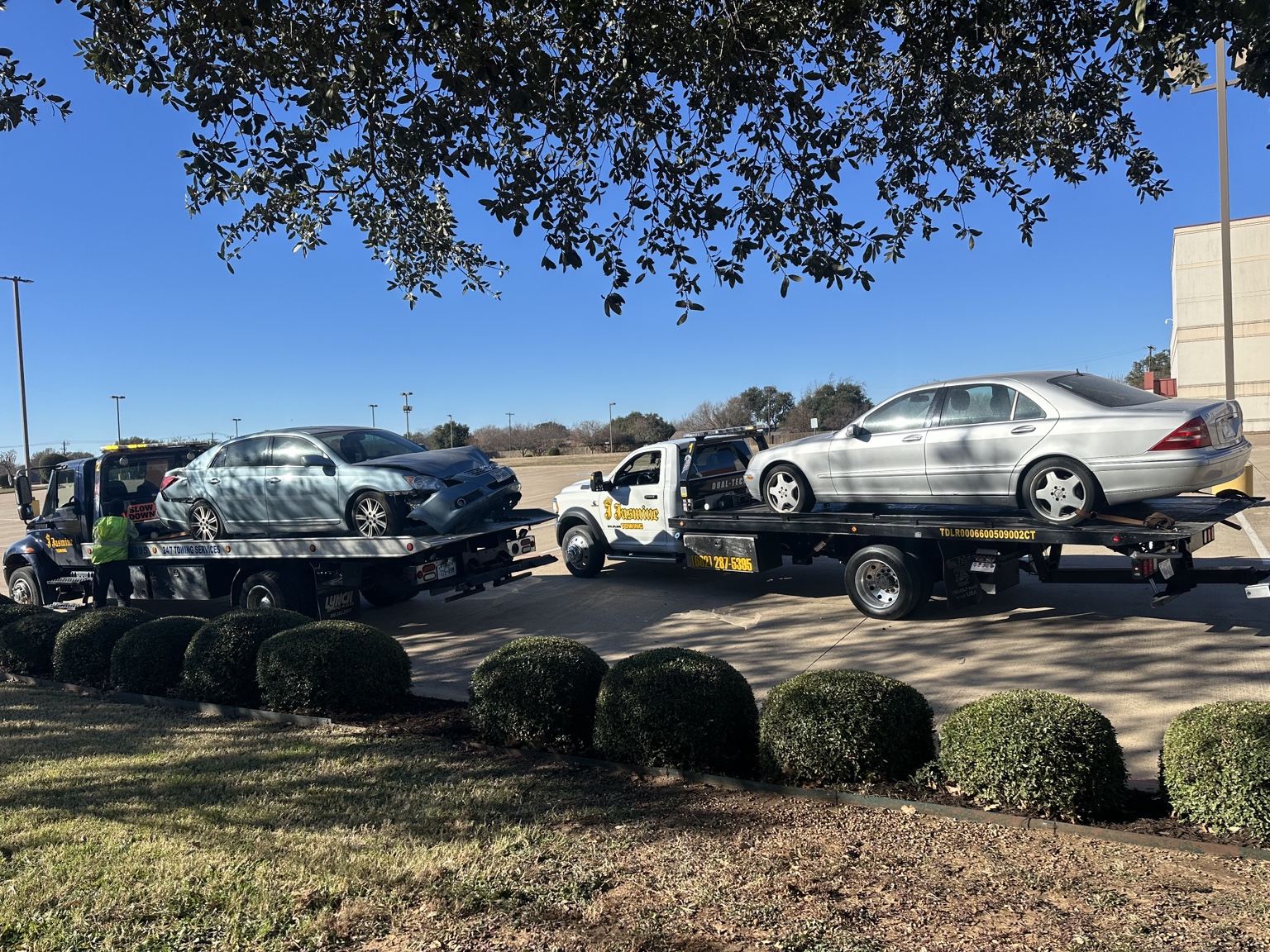 Two flatbed tow trucks carrying passenger cars