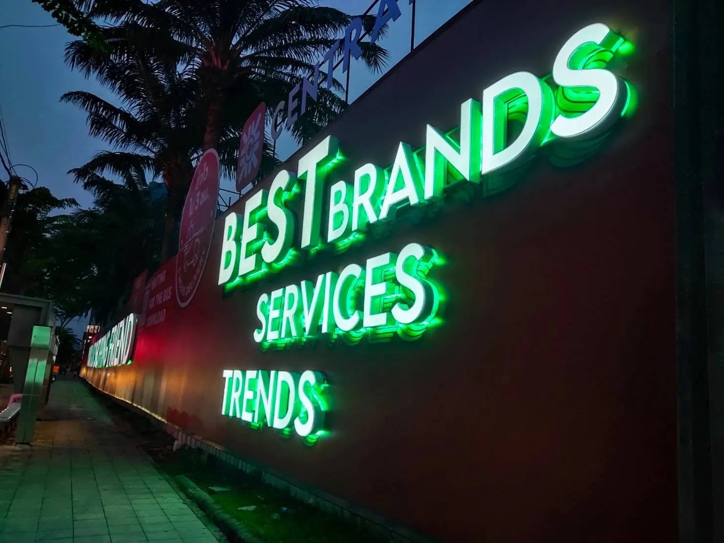 Large halo lit letters along a mall street wall at dusk