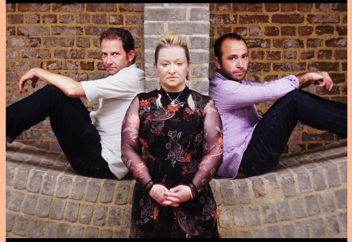 Saul Rose, Eliza Carthy and Dave Delarre, sitting on a wall and looking into the camera.