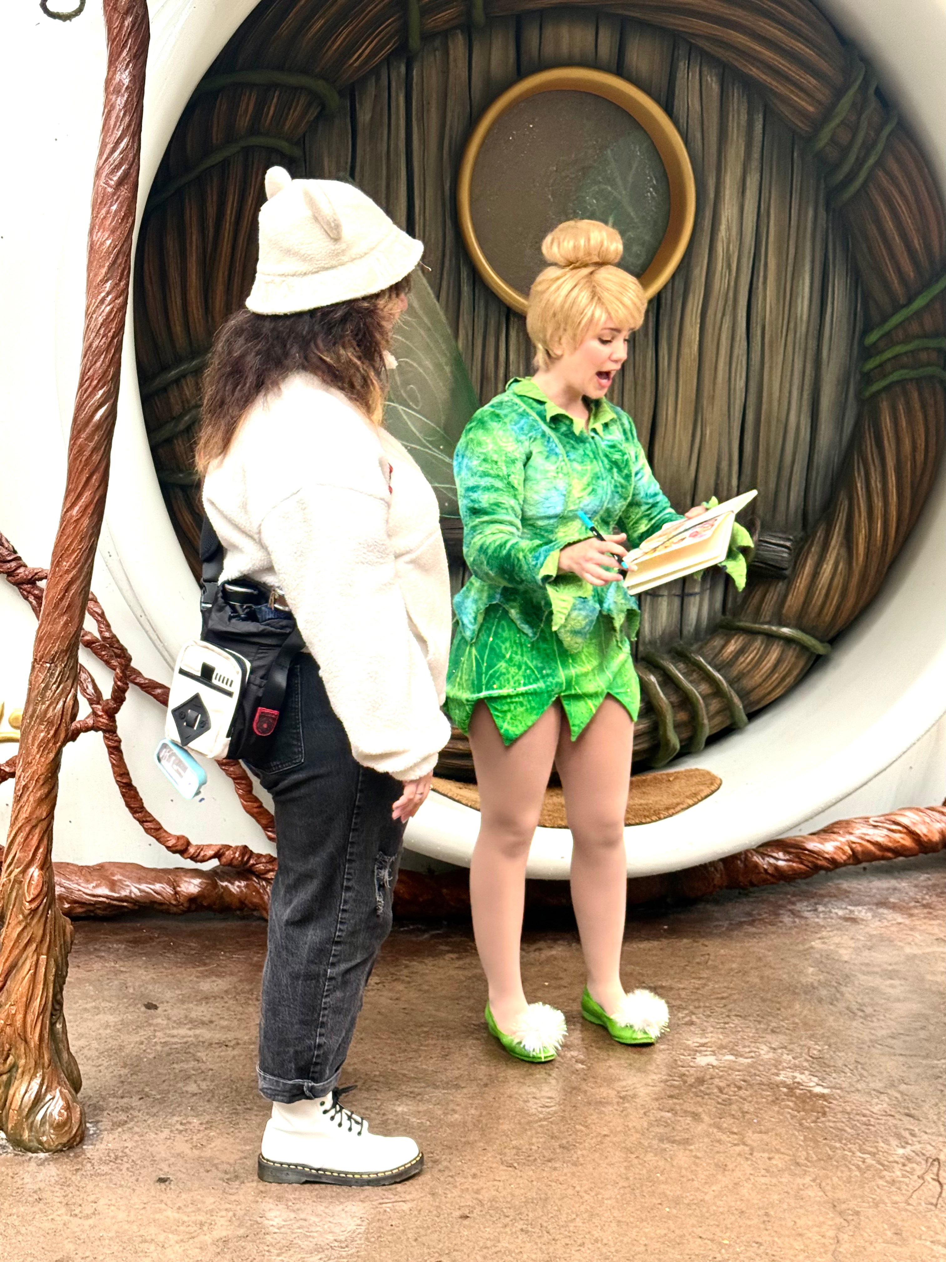 Tinker Bell signs a drawing of her.
