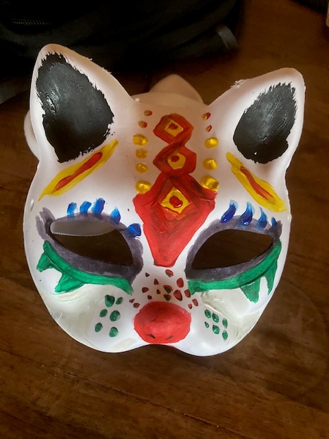 a hand painted cat mask made by a young student for art club.