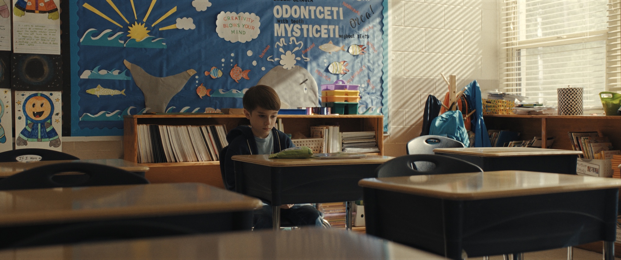 CARY CHRISTOPHER as Alex Lilly sits alone in Miss Gandy's classroom in New Line Cinema’s “Weapons,” a Warner Bros. Pictures release.