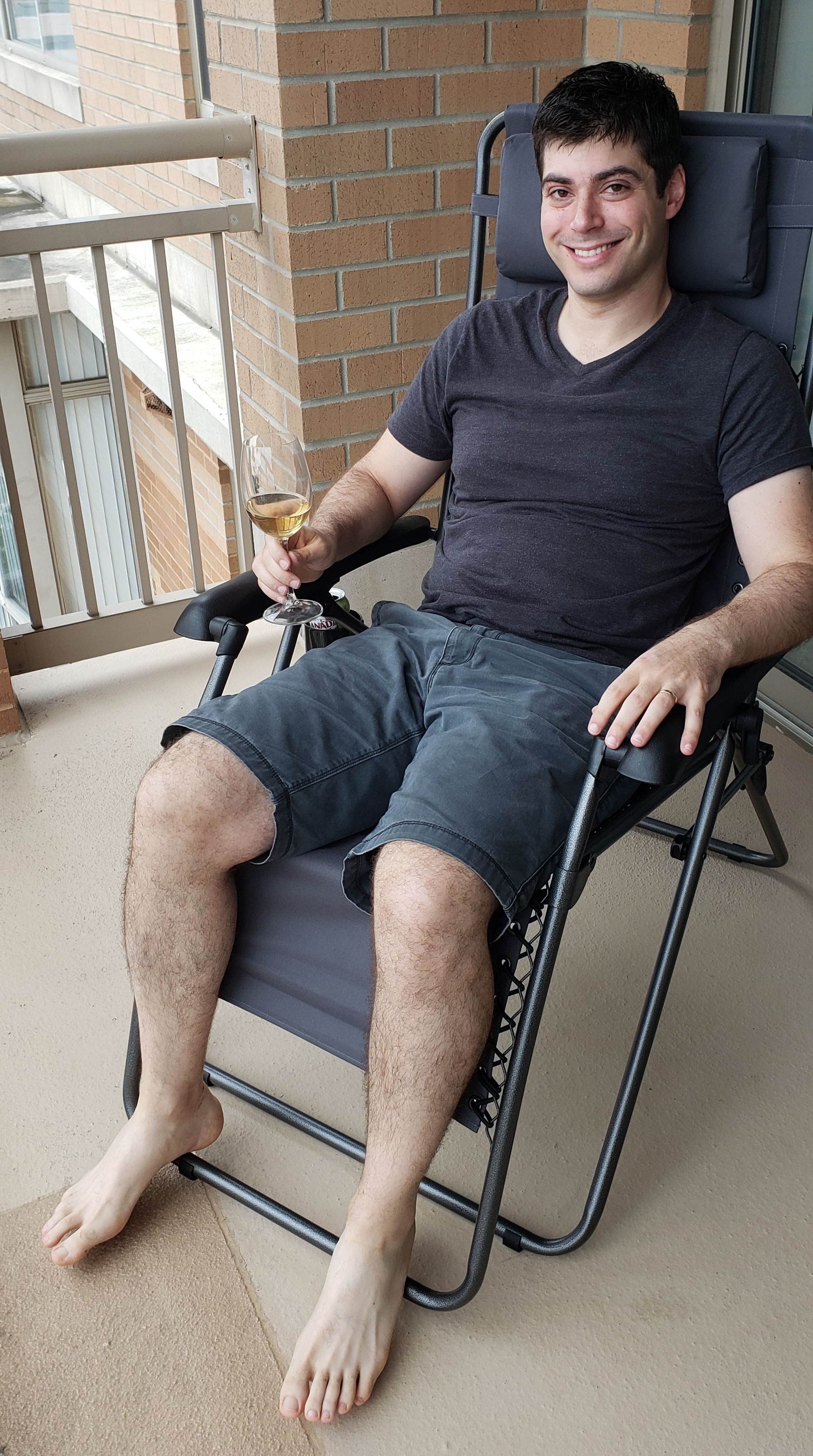A man holding a cocktail while sitting on a zero gravity lounge chair by timber ridge