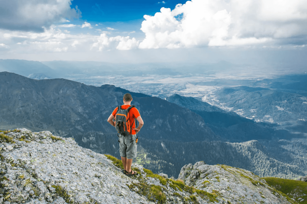 man on top of peak after hiking