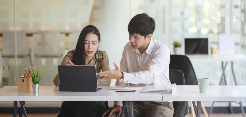 Two colleagues collaborating over a laptop during a business meeting in a bright, modern office.