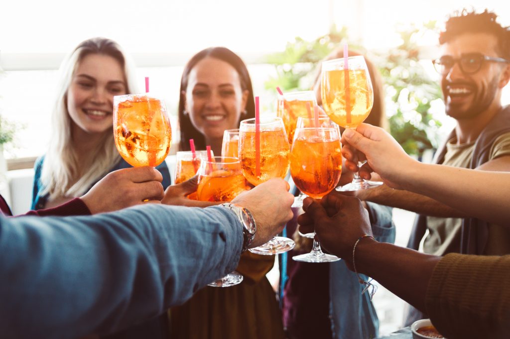 Group of happy friends drinking and toasting friends at a bar re