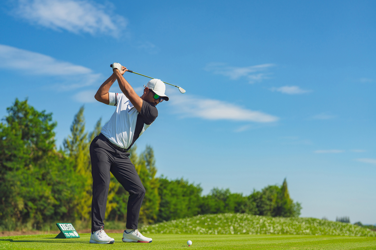 Asian man golfing on the course in summer
