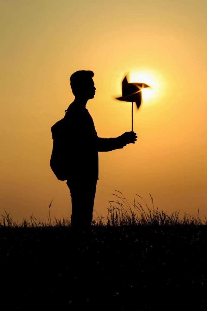 a man holding a wind toy during sunset