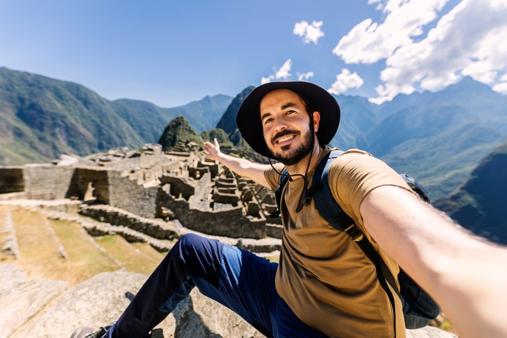 a man taking a selfie at the ancient Inca citadel of Machu Picchu,