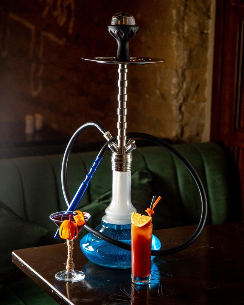 a hookah, also known as a water pipe, with two drinks on a table.